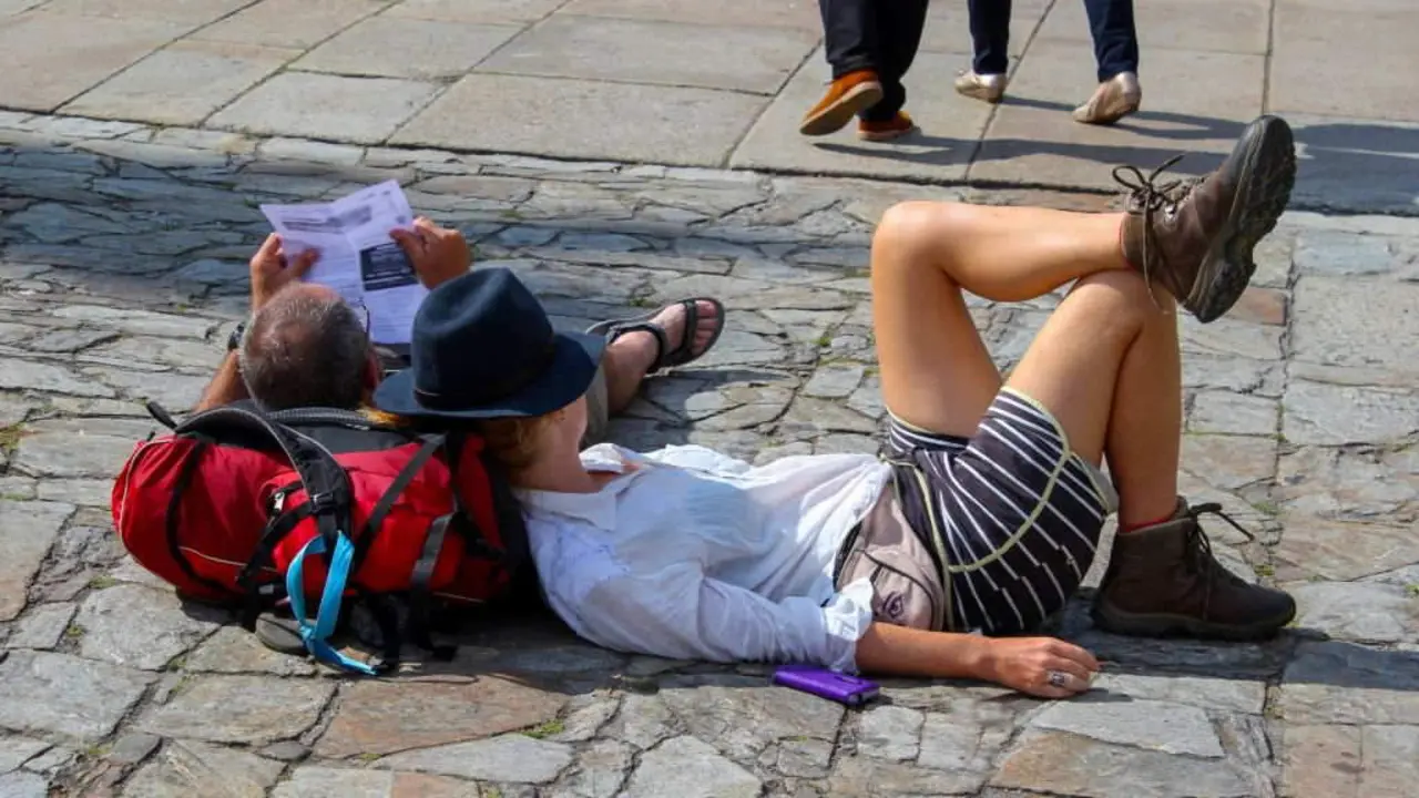 Dous peregrinos descansan na praza do Obradoiro, en Compostela. (Foto: N&oacute;s Diario).