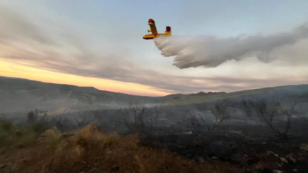 Unha avioneta contraincendios realiza unha descarga sobre un terreo calcinado na Gudi&ntilde;a. (Foto @AT_Brif)