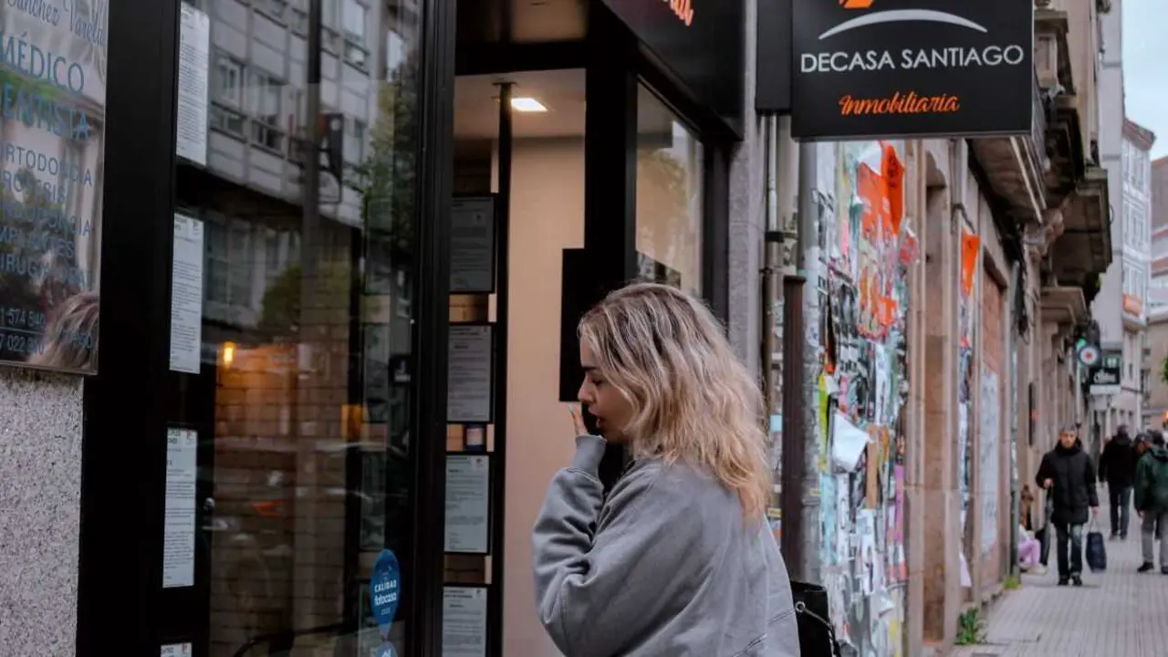 Unha muller ollando os prezos dunha axencia inmobiliaria en Compostela. (Foto: Clara Xantina)