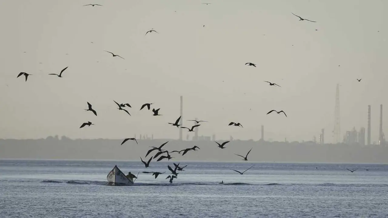 Vista da refiner&iacute;a de Punta Card&oacute;n, ao fondo, e dun pescador no seu barco desde praia de Amuay, na pen&iacute;nsula de Paraguan&aacute;. (Foto: Jes&uacute;s Vargas  dpa )