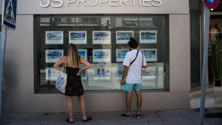 D&uacute;as persoas consultando a oferta de vivenda no escaparate dunha axencia inmobiliaria. (Foto: Mat&iacute;as Chiofalo)