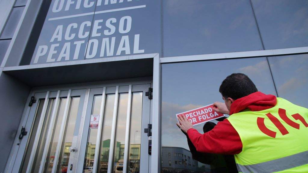 Un sindicalista coloca un cartaz de 'Pechado por folga' ás portas dunha empresa situada no polígono lugués do Ceao. (Foto: Carlos Castro)